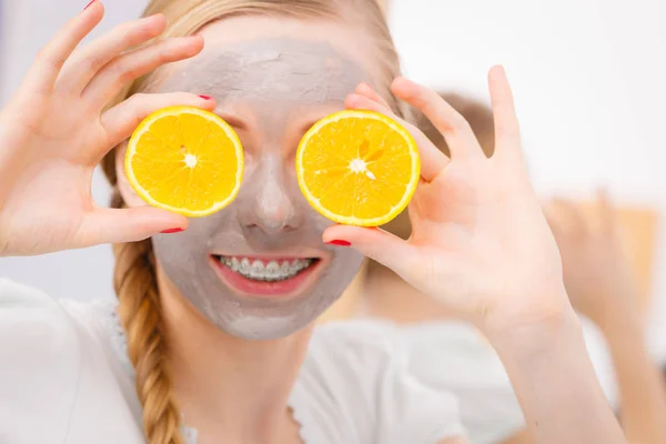 Jovem feliz tendo máscara facial segurando kiwi — Fotografia de Stock