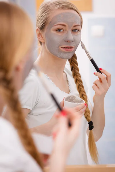 Happy young woman applying mud mask on face — Stock Photo, Image