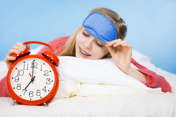Śpiąca kobieta piżamie gospodarstwa zegar — Zdjęcie stockowe