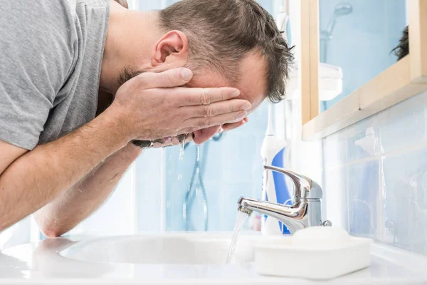 Man washing his face in bathroom
