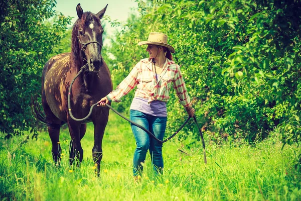 Donna occidentale che cammina sul prato verde con cavallo — Foto Stock