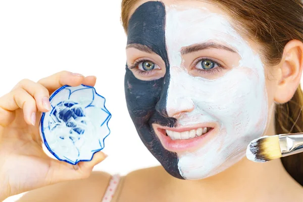 Mädchen schwarze Maske auf halbem Gesicht weißen Schlamm auftragen — Stockfoto