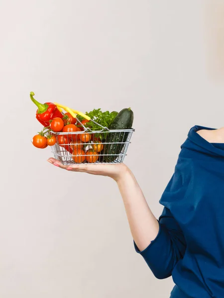 Mão segura carrinho de compras com legumes — Fotografia de Stock