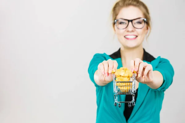 Mujer feliz sosteniendo carrito de compras con bollo dulce — Foto de Stock