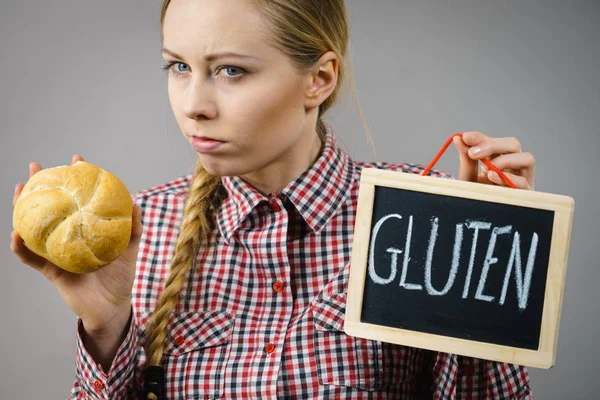 Woman holding board with gluten sign and bun bread