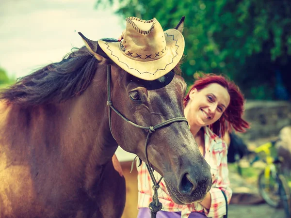 Western woman hugging horse wearing cowboy hat — Stock Photo, Image