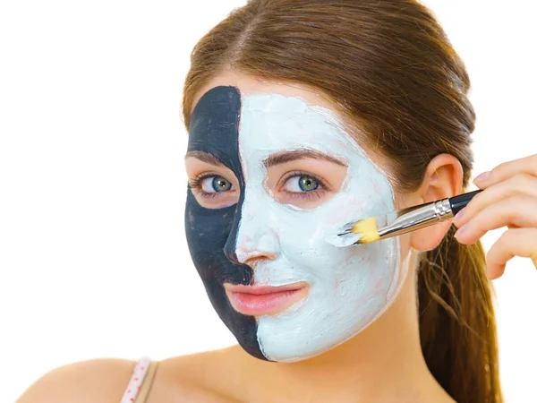Chica máscara negra en media cara aplicar barro blanco —  Fotos de Stock