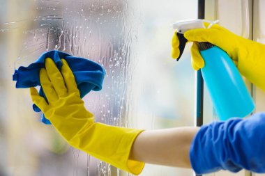 Gloved hand cleaning window rag and spray clipart