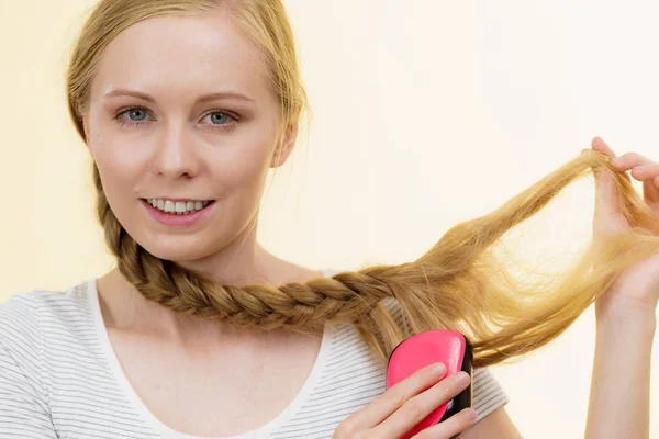 Menina loira com cabelos longos trança mantém escova — Fotografia de Stock