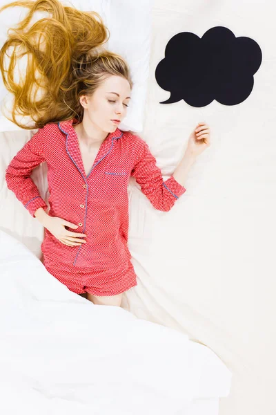 Young woman lying on bed wearing pajamas — Stock Photo, Image