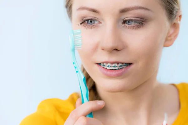 Kvinna leende rengöring tänder med hängslen — Stockfoto