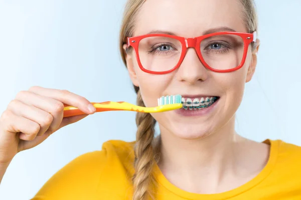Žena se usmívá čištění zubů s rovnátky — Stock fotografie