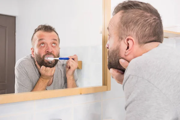 Cara entediado escovar os dentes no banheiro — Fotografia de Stock