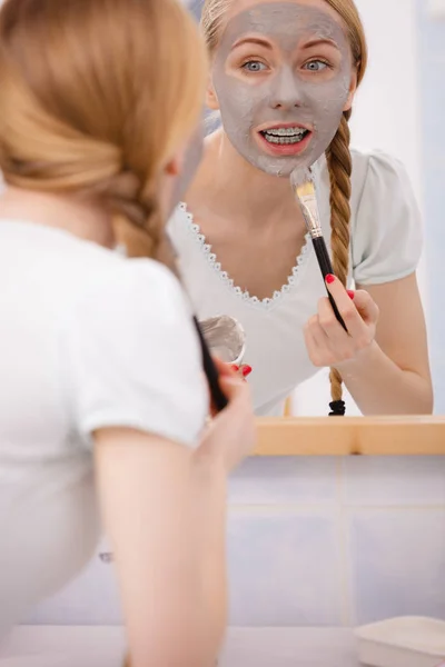 Vrouw met grijze klei modder masker op haar gezicht — Stockfoto