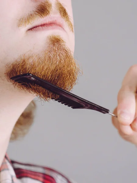 Homme brossant sa barbe à l'aide d'un peigne — Photo