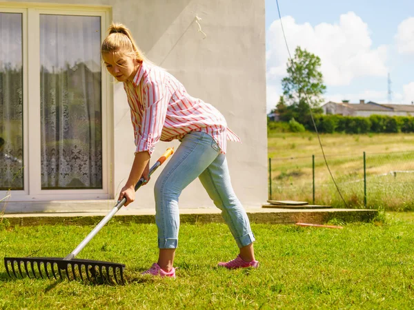 Woman using rake to clean up garden — Stock Photo, Image