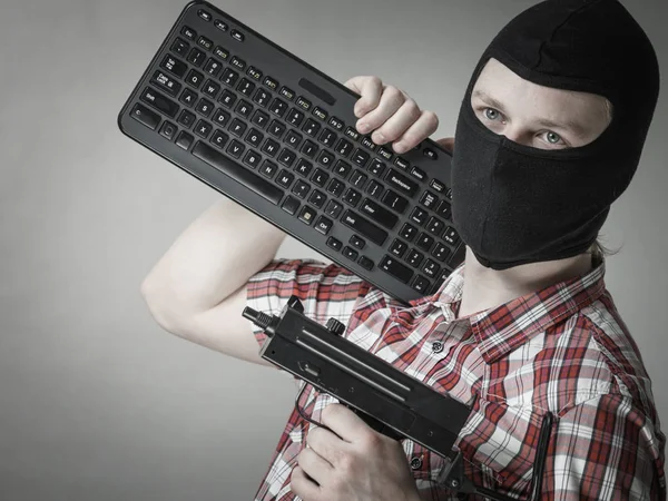 Mann mit Sturmhaube mit Tastatur und Waffe — Stockfoto