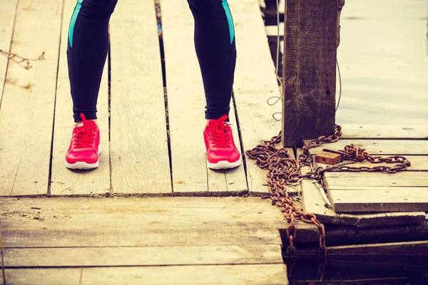 Тонкие здоровые ноги в красной спортивной обуви на деревянном пирсе — стоковое фото
