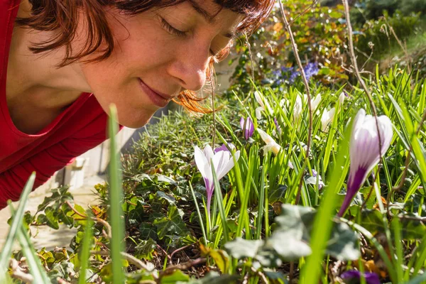 Woman smelling white crosus on grass — Stock Photo, Image