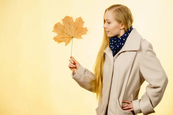 Женщина держит оранжевый осенний лист — стоковое фото