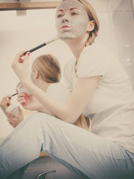 Mujer aplicando con la máscara de barro cepillo de barro en su cara — Foto de Stock