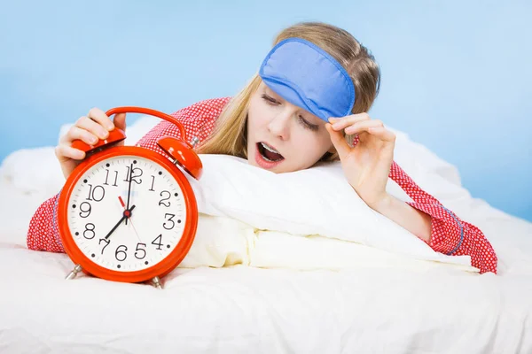 Спляча жінка в піжамі тримає годинник — стокове фото