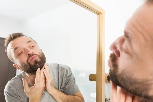 Muž, který se dívá na vousy v zrcadle — Stock fotografie