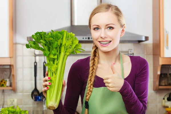 Mulher na cozinha detém aipo verde — Fotografia de Stock