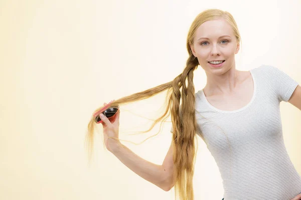 Sarışın kız uzun saçlarını tarıyor — Stok fotoğraf