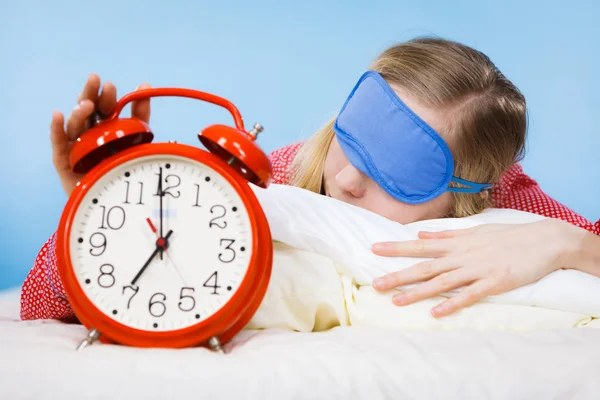 Schlafende Frau im Schlafanzug hält Uhr — Stockfoto