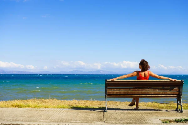 Toeristische vrouw op bankje genieten van zeezicht — Stockfoto