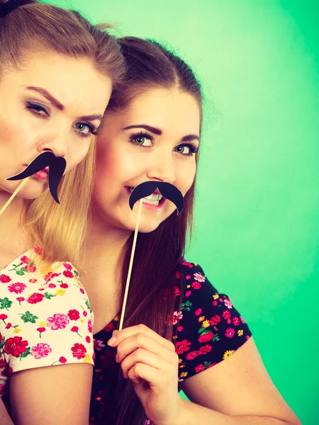 Twee gelukkige vrouwen houden van valse snor op stick — Stockfoto