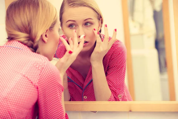 Ung Blond Kvinna Som Applicerar Återfuktande Hudkräm Ansiktet Tittar Badrumsspegeln — Stockfoto