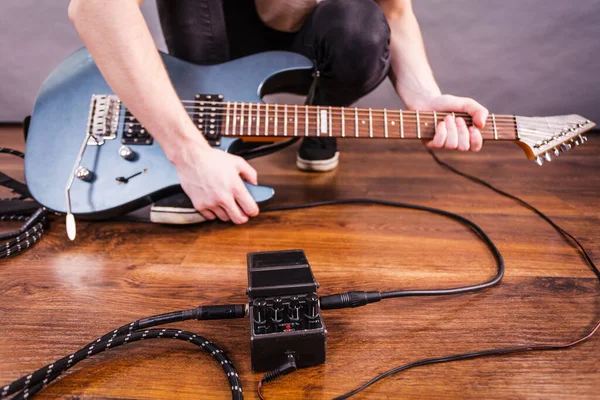 Man with musical instrument setting up guitar audio stomp box effects and cables in music studio