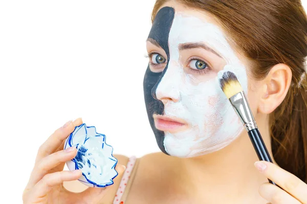 白い泥を肌をきれいにするために適用する半分の顔に粘土のカルボ黒マスクを持つ女性 女の子は油性の肌の世話をする 美容方法だ スキンケア — ストック写真
