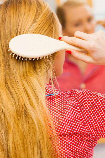 年轻女人在浴室里梳理着她长长的金发 用刷子 照镜子 照顾的女孩使她的发型焕然一新 理发概念 — 图库照片