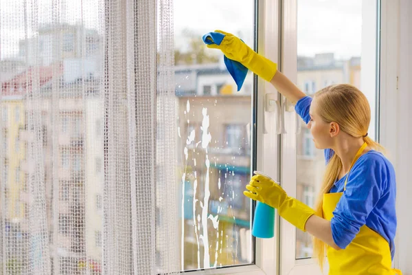 ラグとスプレー洗剤で自宅で黄色の手袋のクリーニングウィンドウペインの若い女性 清掃コンセプト — ストック写真