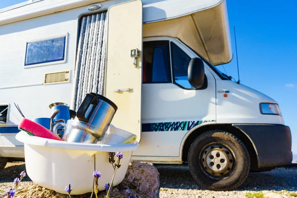 Bowl full of dirty dishes outdoor against camper vehicle. Washing up on fresh air. Adventure, camping on nature, dishwashing outside. Longing for an RV dishwasher.