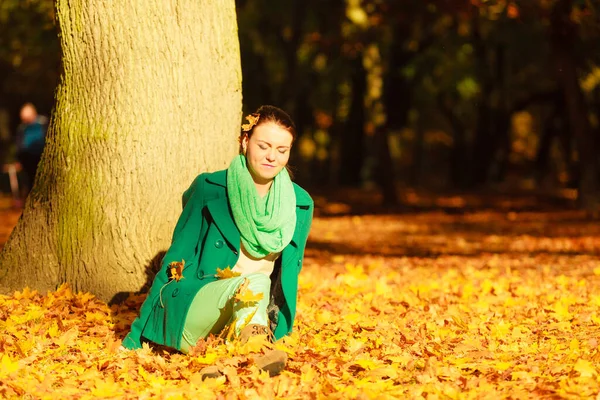 秋の葉の上に座っている女性は 森の公園で美しい秋の天気を楽しんでいます 黄金色の葉が多い — ストック写真