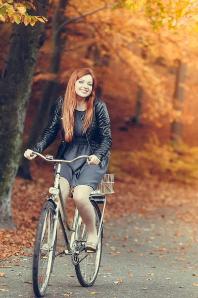 ウッドランド自然屋外リラックスレジャーコンセプト 公園での赤毛の女性のサイクリング 秋の森の中を自転車に乗っているジンジャーガールの笑顔応援 — ストック写真
