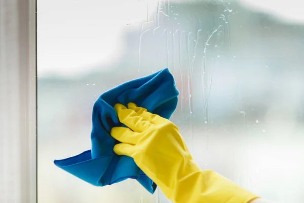 青いラグとスプレー洗剤で黄色の手袋のクリーニングウィンドウで女性の手 春の掃除 家事のコンセプト — ストック写真