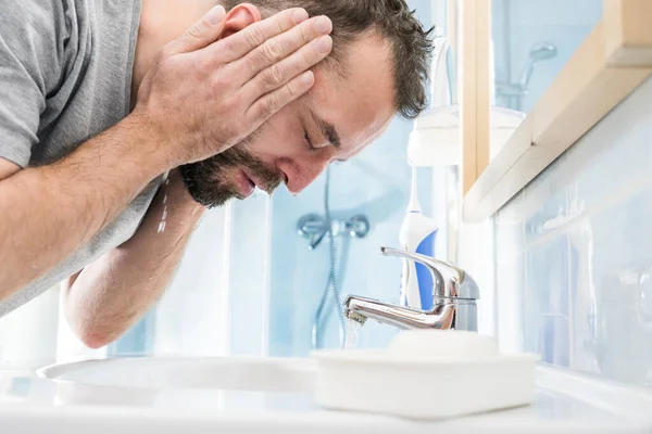 男は自分の顔に水を撒き 自分自身を洗い 個人的な衛生管理をする 朝の気分がいい — ストック写真