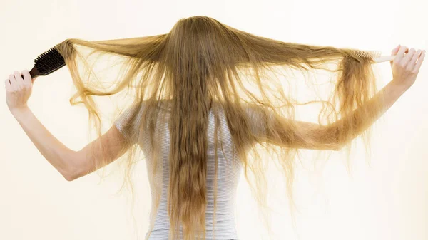 ブロンドの女性は 彼女の非常に長い髪を持ってブラシで ヘアケアの悪い10代の女の子 バックビュー — ストック写真