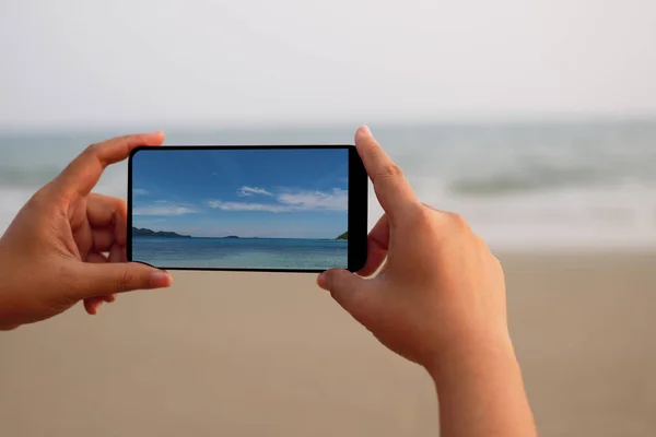 Bir fotoğrafta denizin bir smartphone tutan bir kadın.