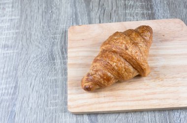 Kruvasan tek parça bir ahşap kesme tahtası ve tablo gri Wood yerleştirilir