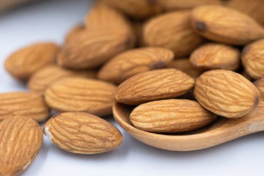 Bir tahta kaşık badem tohum ve kırık bir tohum ile dış beyaz arka plan üzerinde. Odak alan sığ derinliği seçin