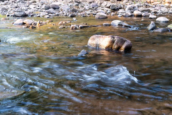 La luz del sol golpeó las rocas en el arroyo con agua fría y clara f —  Fotos de Stock