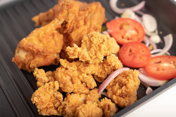 Pollo frito en una sartén negra con cebolla y tomate en rodajas —  Fotos de Stock