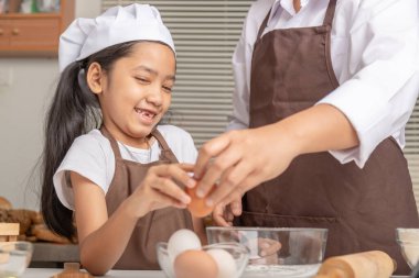 Anne ve kızı mutlulukla pişirmek için yumurta toplamaya yardım ediyorlar. Odaklanma derinliğini seç.
