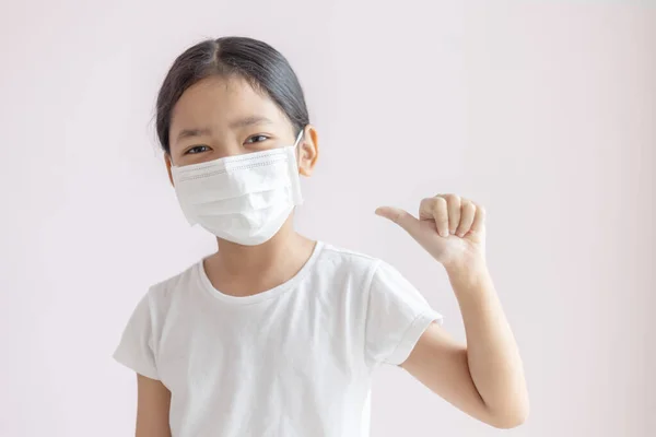 Koruyucu tıbbi maske takan Asyalı küçük bir kız. Grip salgını, Coronavirüs veya COVID-19 salgını ve sisli hastalıklara karşı koruma.